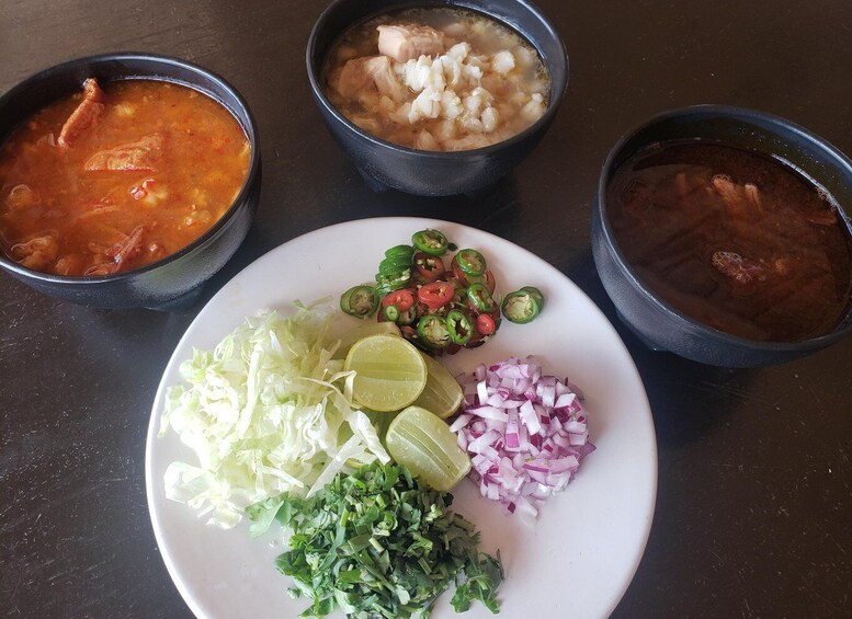Three bowls of soup and a plate with vegetables. 5