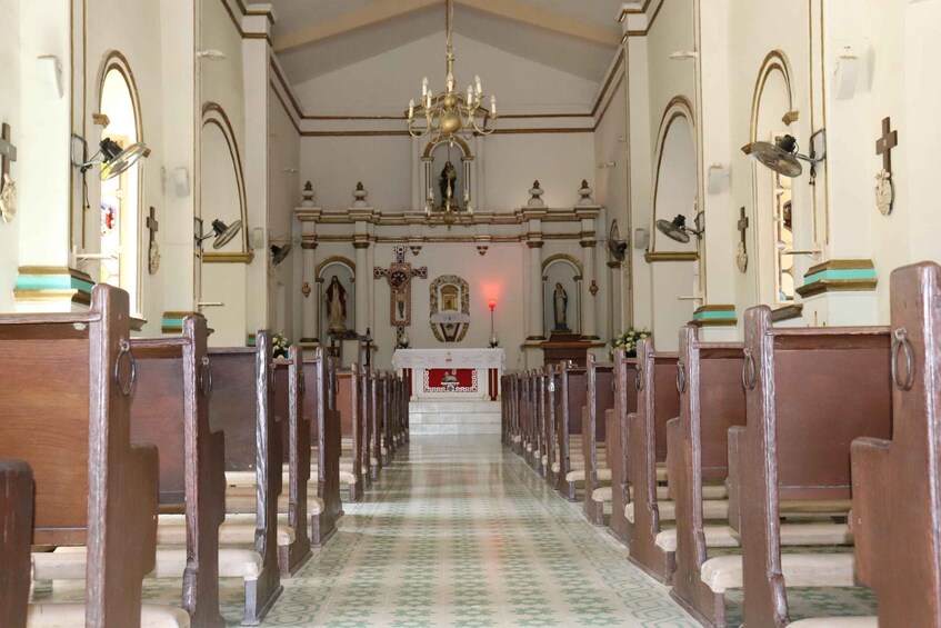 An interior of a church with wooden pews, a chandelier, and a patterned floor. 3