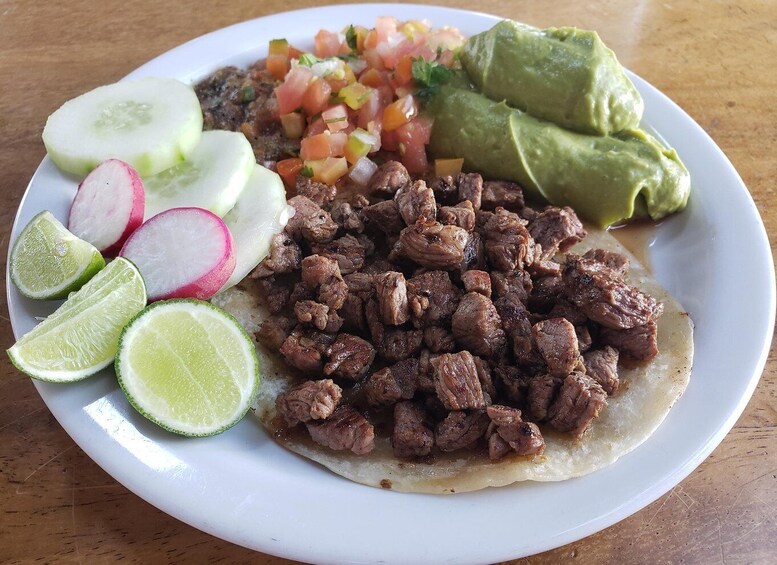 A plate of beef, radishes, lime, and avocado. 1