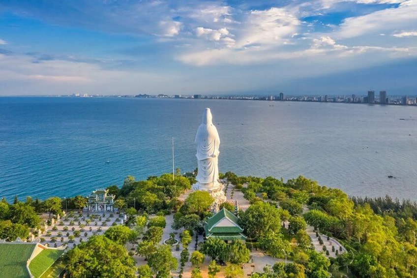 A large white statue on a hill overlooking a body of water with a city skyline in the distance. 5