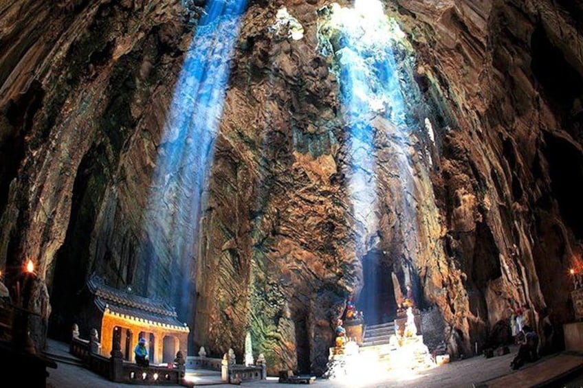 A cave with a waterfall, a small temple, and a statue. 2
