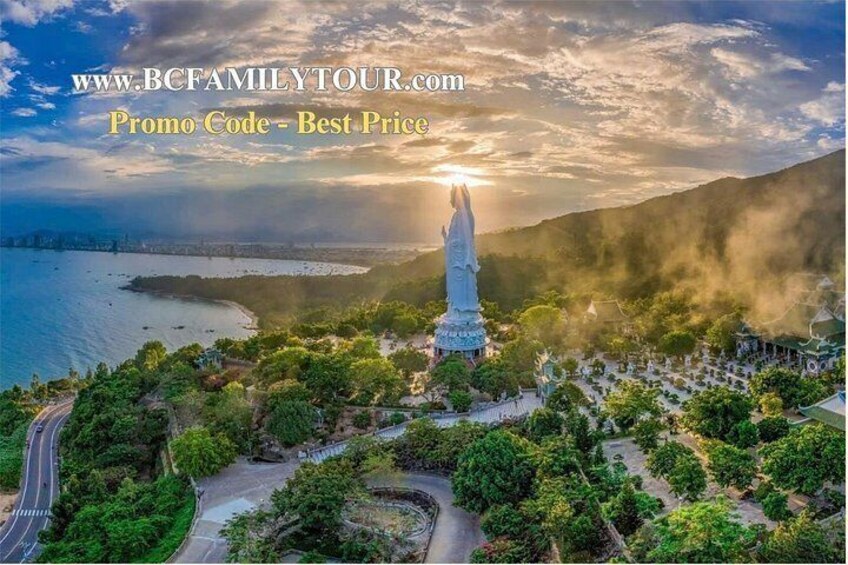 A statue surrounded by greenery, a body of water, and a city skyline in the background. 5