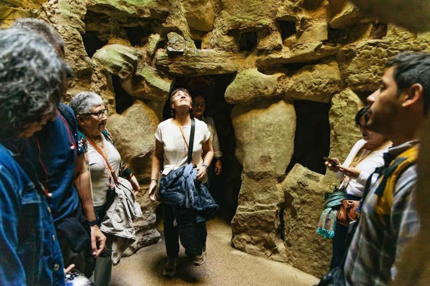 A group of people walking through a rocky cave passage. 5