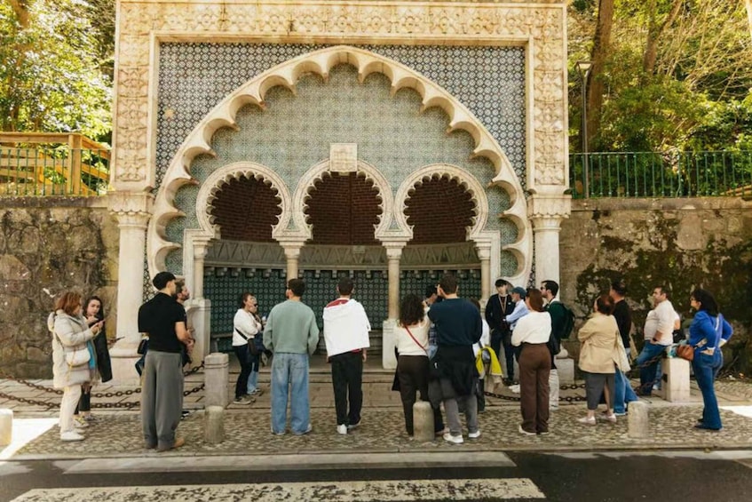 A group of people standing in front of a building with ornate arches and patterned tiles. 2