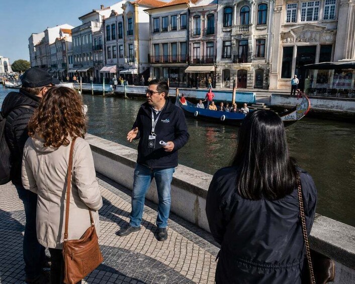 People standing by a canal with boats and historic buildings in the background. 5