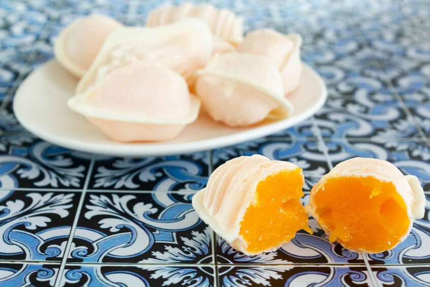 A plate of round pastries with a creamy filling, placed on a patterned tile tablecloth. 2