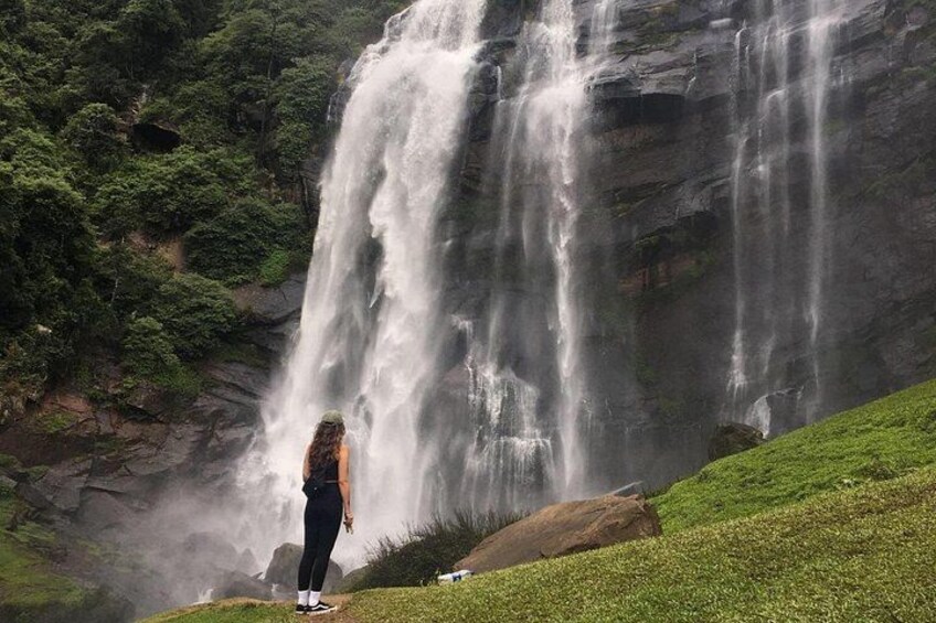 Ein Wasserfall stürzt über eine felsige Klippe, umgeben von üppiger Vegetation. 1