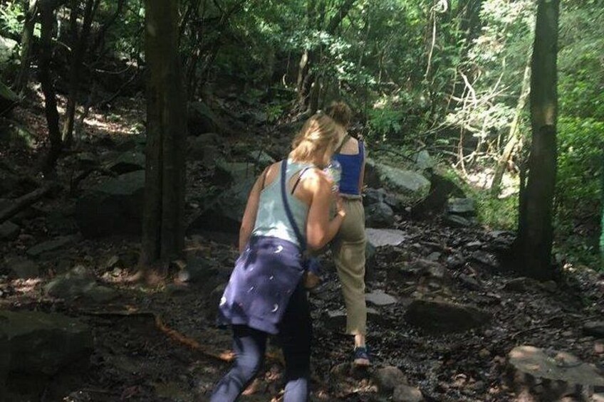 Zwei Wanderer in einem bewaldeten Gebiet mit Felsen und Bäumen. 3