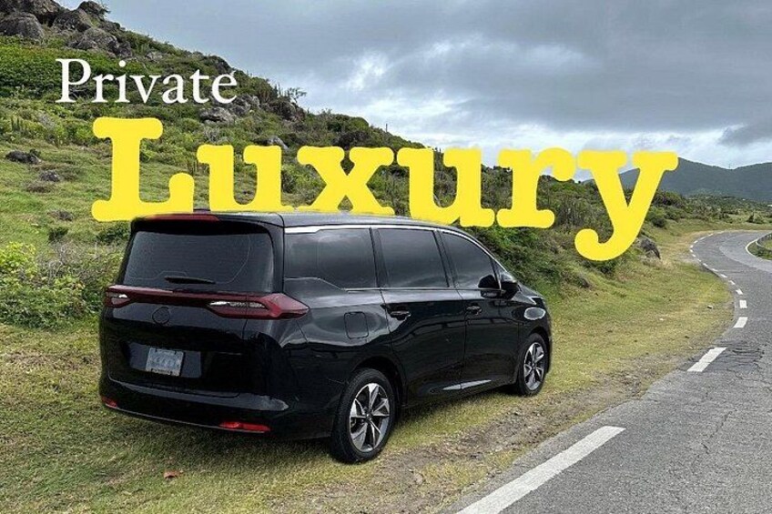 A black SUV parked on a grassy roadside with a mountainous landscape in the background. 2