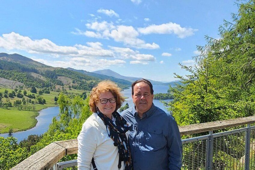 A couple standing on a wooden deck overlooking a river and hills. 3
