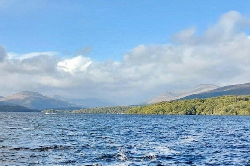 Un lago tranquilo con un bote, montañas distantes y una orilla bordeada de bosque. 3