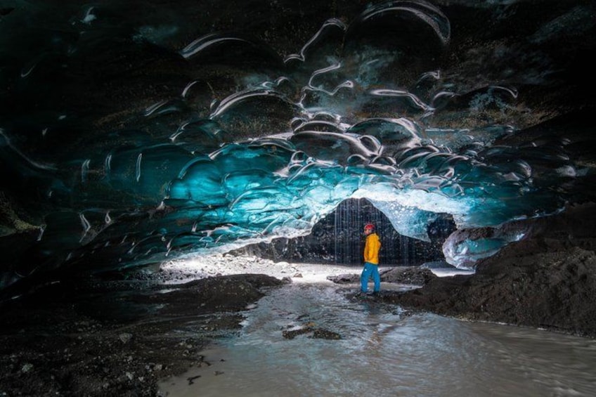 Une personne se tient dans une grotte, entourée de formations de glace. 4
