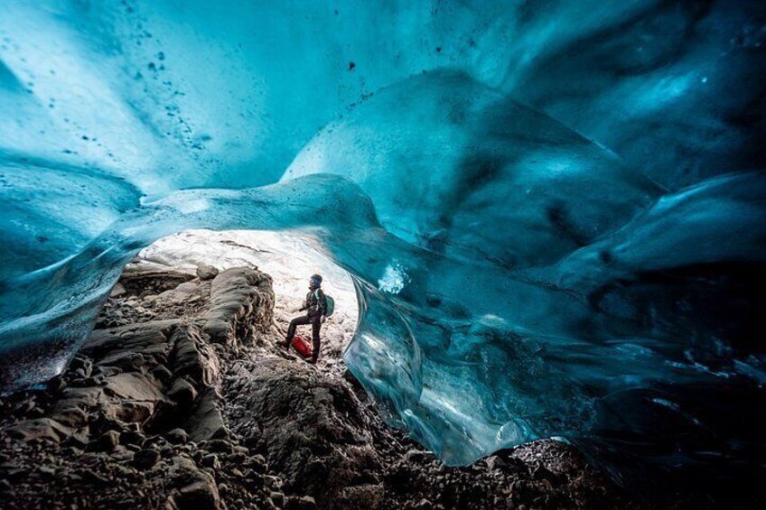 Une personne se tient dans une grotte de glace, entourée de formations de glace bleues. 1
