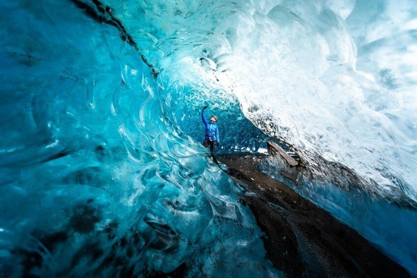 Une personne vêtue d’une veste bleue, à l’intérieur d’une grotte de glacier. 2