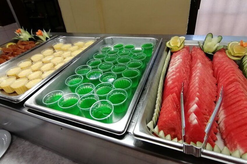 A buffet with various food items including sliced fruits and beverages in cups. 4