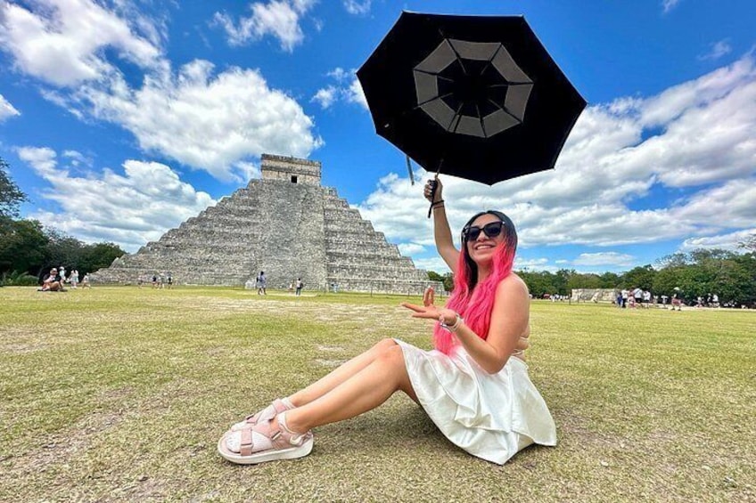 A person sitting on grass with a pyramid in the background. 4