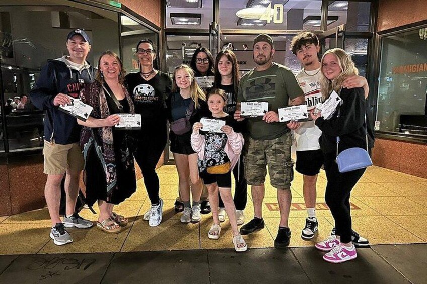 A group of people holding certificates in front of a building with a sign that reads '40'. 5