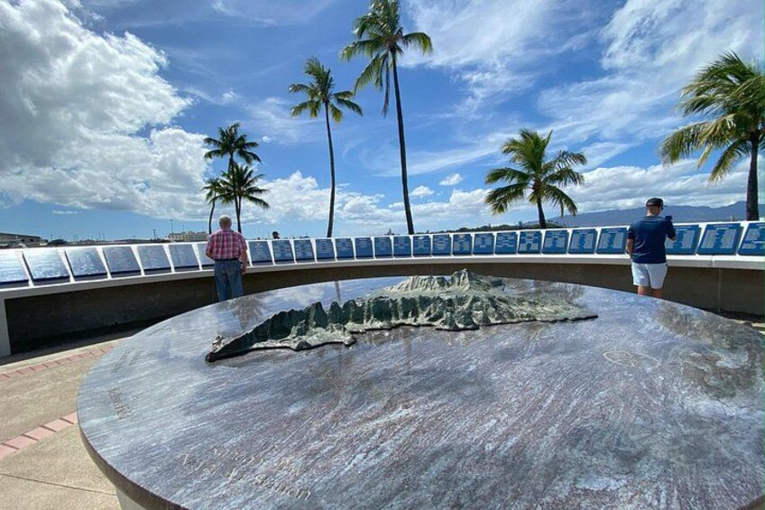 En stor, rund stenskulptur med en detaljeret overflade, palmer og en klar himmel. 2