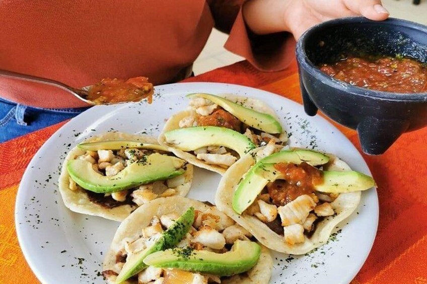 A plate of tacos with avocado and a bowl of salsa. 2