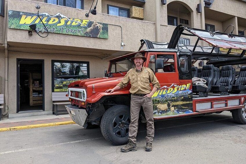 A red truck parked in front of a building with a sign that reads 'WILDSIDE 4x4 Tours'. 3
