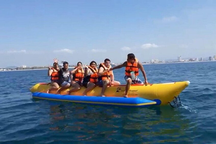 A group of people on a yellow inflatable raft with blue trim, floating on water. 1