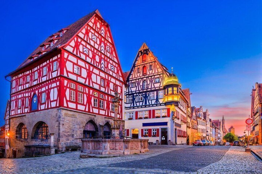 A cobblestone street lined with traditional half-timbered buildings, a clear sky, and a sunset. 2
