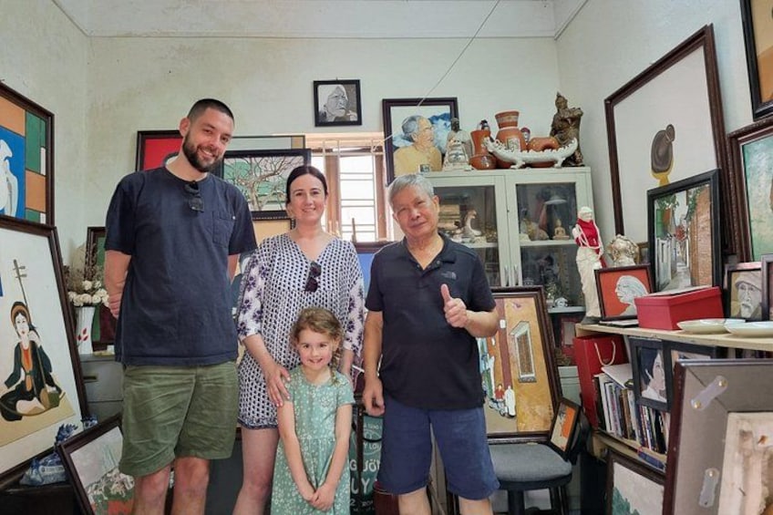 A family in a room with various framed artworks and sculptures. 5