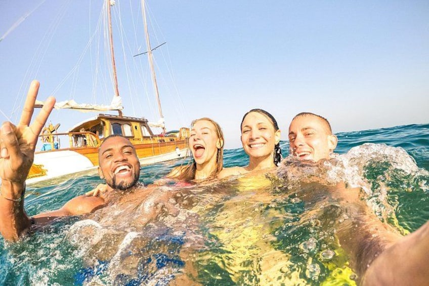 Eine Gruppe Menschen auf einem Boot im Ozean, im Hintergrund ein Segelboot. 5