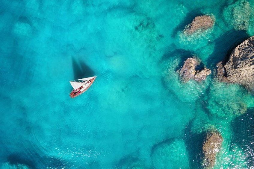 Ein kleines Boot auf türkisfarbenem Wasser, das eine klare Sicht auf Felsformationen bietet. 1