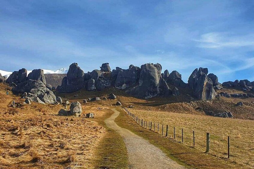 A gravel path leading through a rocky landscape with large boulders and a clear sky. 3