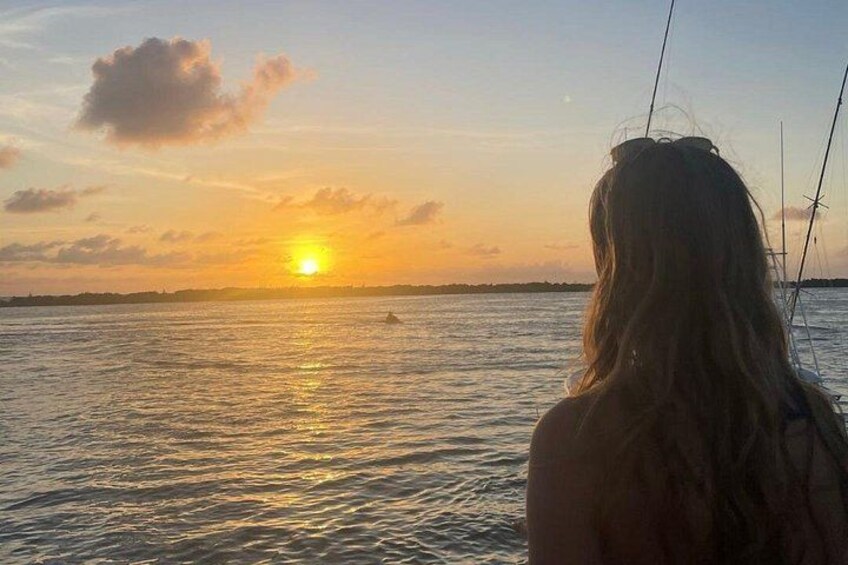 A sunset over a body of water with a silhouette of a person. 3