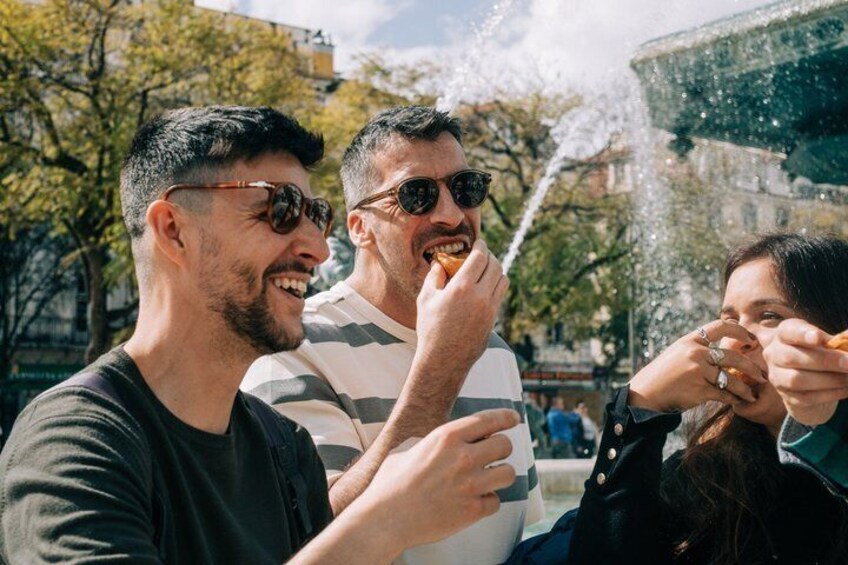 Three people enjoying a water fountain in an outdoor setting. 3
