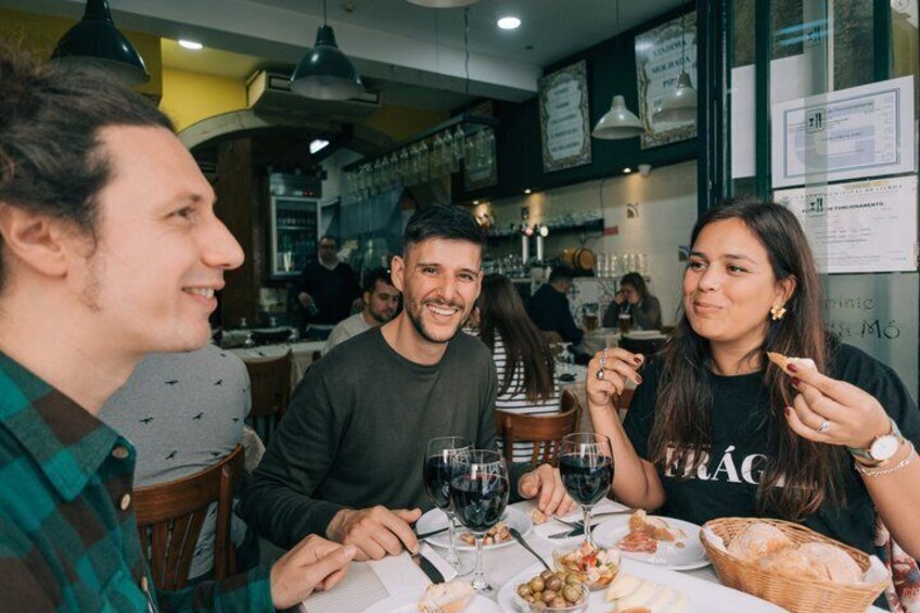 A group of people dining at a restaurant with wine glasses and a basket of bread on the table. 1