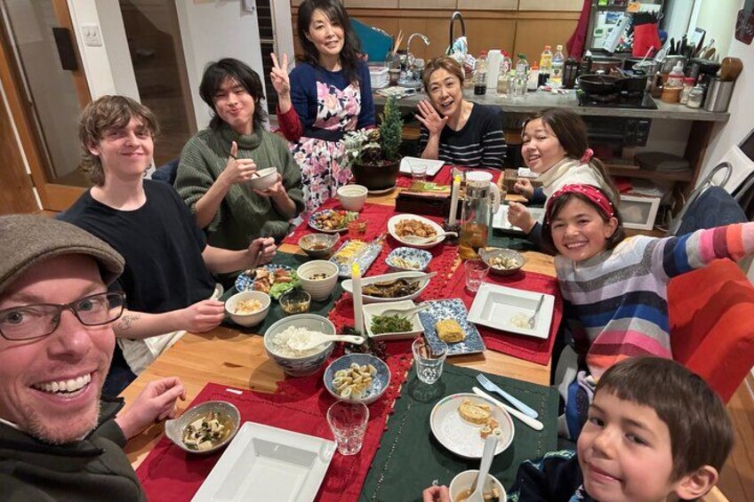 Un groupe de personnes est assis autour d’une table, devant divers plats et boissons. 2