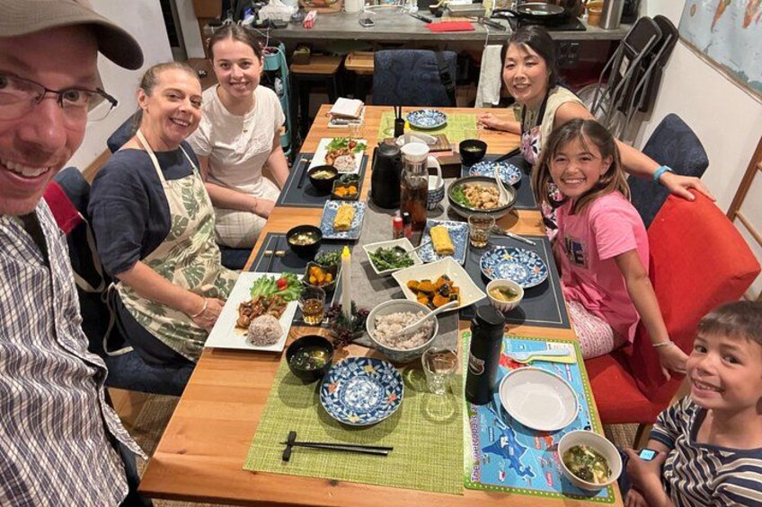 Un groupe de personnes est assis autour d’une table en bois, devant divers plats et boissons. 3