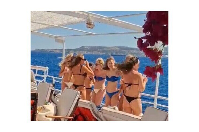 A group of women in bikinis on a boat with a view of the sea and a distant coastline. 5