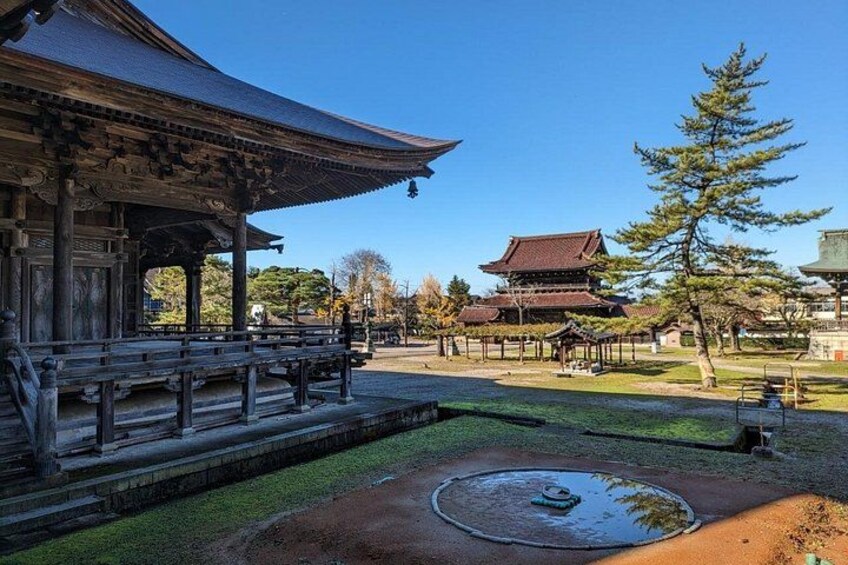A traditional Japanese temple with a large pagoda, a koi pond, and a well-maintained garden with trees and a stone path. 4