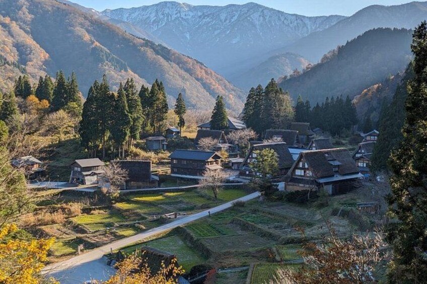 A village nestled in a valley with houses, trees, and mountains in the background. 2