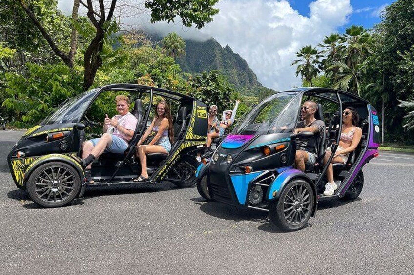 Two tuk-tuks on a road with passengers. 3