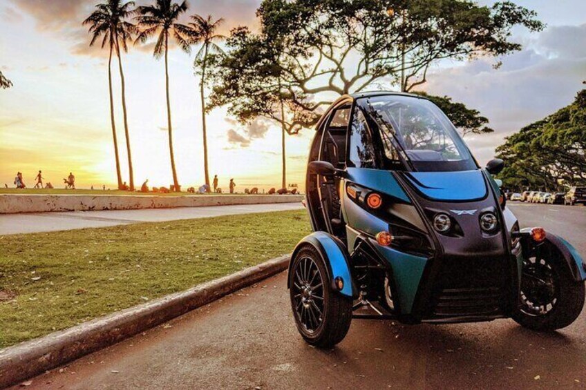 A blue and black three-wheeled vehicle parked on a paved path. 5