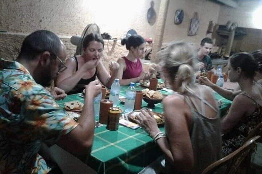 Un gruppo di persone sedute attorno a un tavolo con cibo e bevande. 3