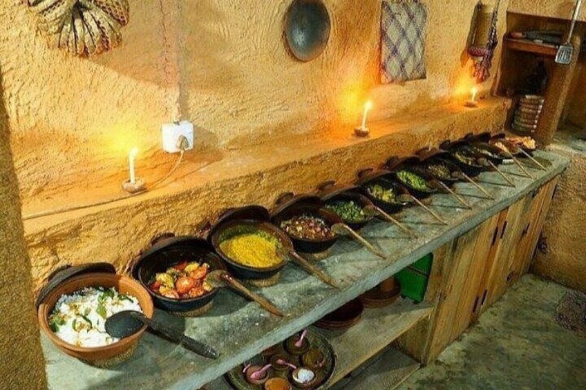 Un buffet con diversi piatti presentati in contenitori neri, un bancone in legno e candele appese al muro. 1