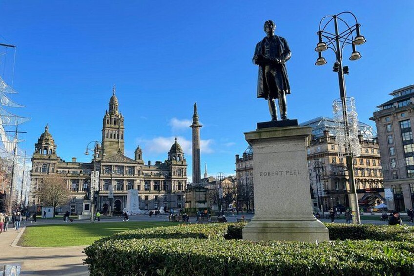 A statue of Robert Peel, a building with a tower, and a street lamp. 1