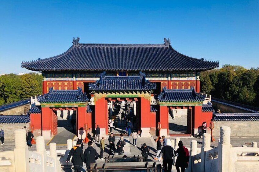 En traditionell koreansk port med ett tak täckt av tegelpannor och röda väggar, omgiven av besökare. 3