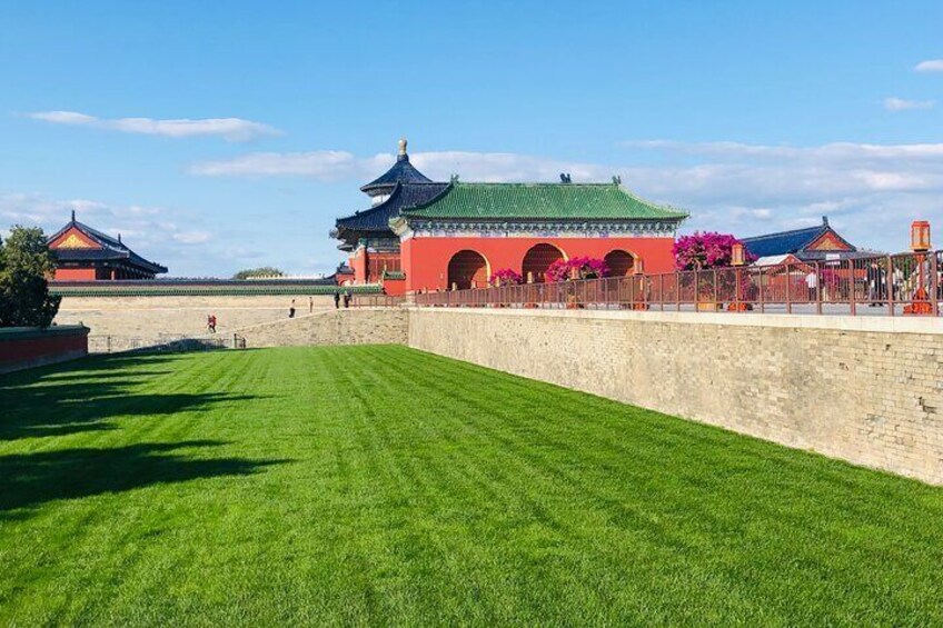 Un bâtiment traditionnel chinois, doté d’un toit vert et de murs rouges, entouré d’un mur de pierre et d’une pelouse bien entretenue. 1