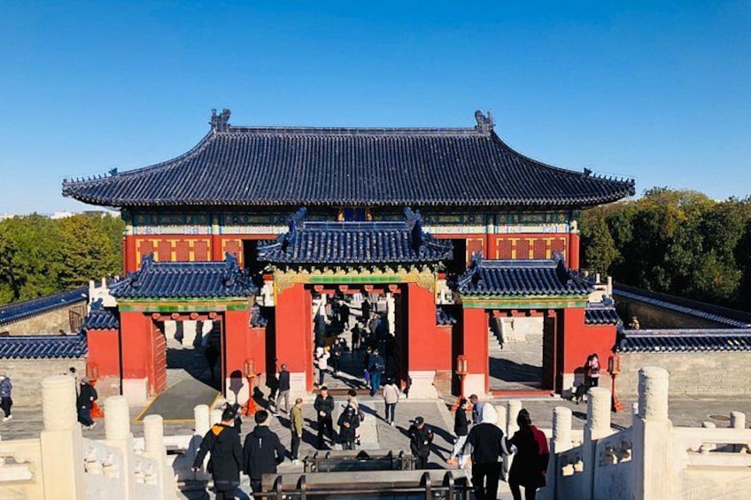 A traditional Chinese gate with red pillars and blue tiles, surrounded by visitors. 4