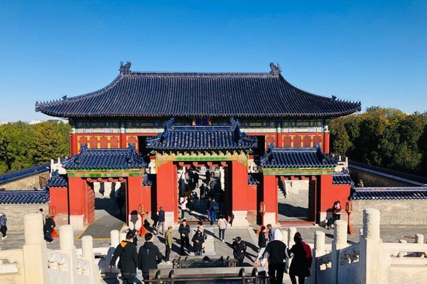A traditional Korean gate with a curved roof and red pillars, surrounded by a stone pathway with visitors. 4
