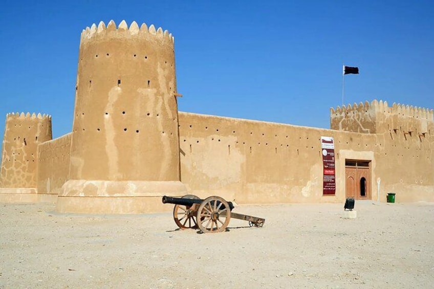 Una fortaleza histórica con un cañón, cielo despejado y una bandera. 2