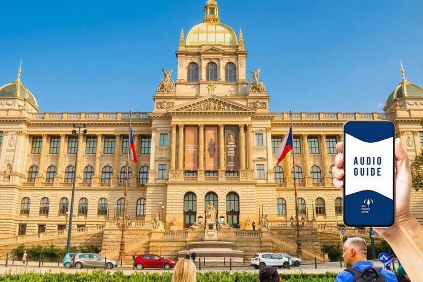 A grand building with a dome and columns, flags, and a person holding a smartphone with an audio guide app. 1