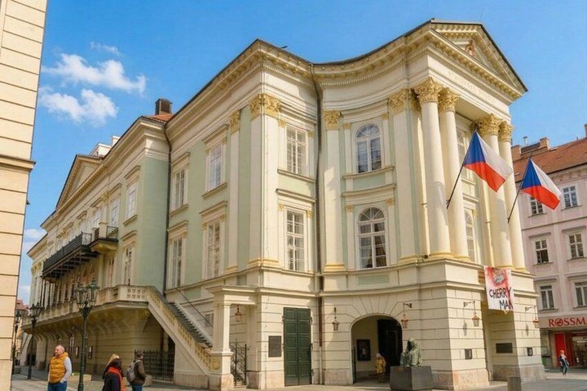 A historic building with classical architecture, flags, and a street sign. 4